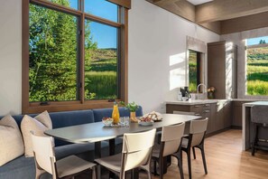 A modern kitchen with a dining area, large windows with a view of greenery, and a built-in oven. - Abode at White Clouds, hot tub, Sun Valley, minutes to skiing (Sun Valley)