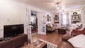 A living room with a television, a sofa, a coffee table, and a fireplace. - Schilling House (Bolivar)