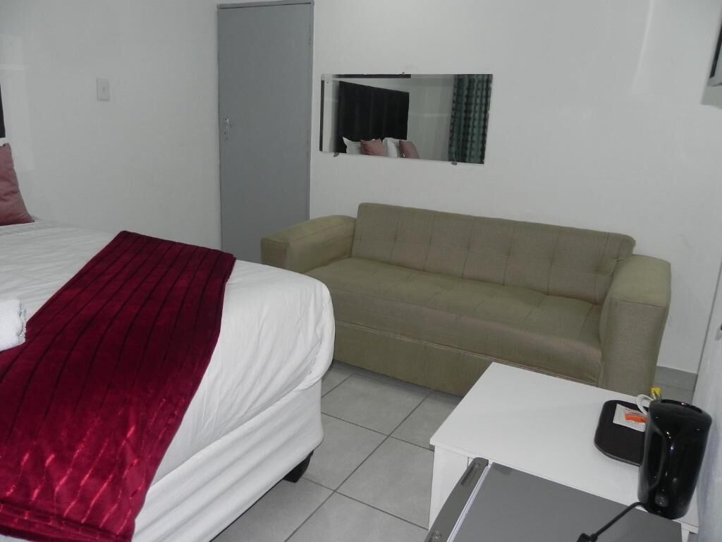 Une chambre d’hôtel avec un lit, un canapé, une petite table et un miroir au mur.