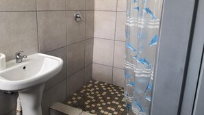 A bathroom with a white sink, tiled walls, and a checkered floor. - De Bliss Lodge (Newtown)