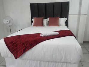 A bed with a white comforter, a red throw blanket, and two pillows. - De Bliss Lodge (Newtown)