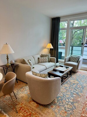 Ein Wohnzimmer mit einer Couch, Sesseln, einem Couchtisch und einem gemusterten Teppich.