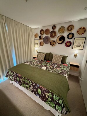 Une chambre avec un grand lit, un mur recouvert de paniers tressés et une vue sur l’extérieur.