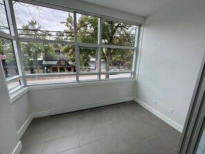 Ein Zimmer mit großem Fenster, weißen Wänden und Fliesenboden.