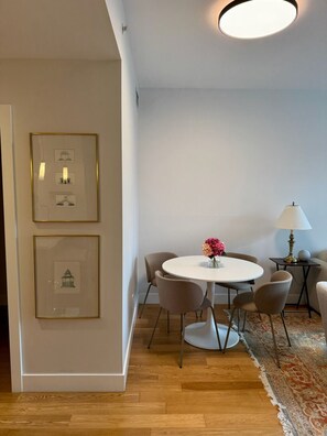 Un coin repas avec une table ronde, des chaises, une lampe et des tableaux encadrés accrochés au mur.