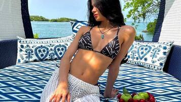 Una persona sentada en un sofá exterior con estampado, mirando al mar.