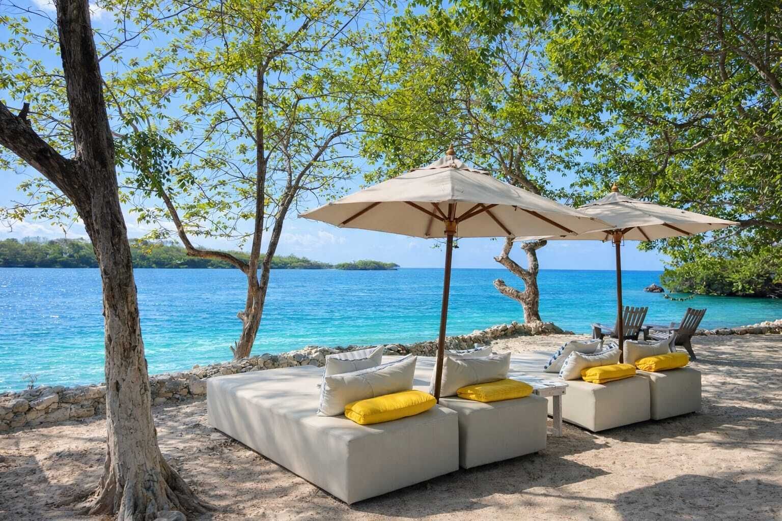 A beachside lounge with outdoor seating and umbrellas, overlooking a clear blue sea.