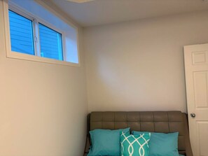 A bedroom with a window, a door, and a bed with two pillows.
