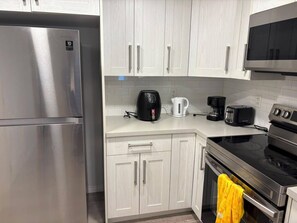 A modern kitchen with stainless steel appliances, white cabinetry, and a microwave above the stove.
