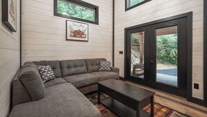 A modern interior with a sectional sofa, a small table, and a large sliding glass door leading to an outdoor area. - Home Sweet Smoky (Pigeon Forge)