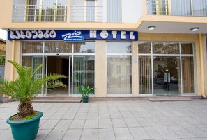 A hotel with a signboard, large windows, and potted plants in front. - Rio Batumi (Batumi)