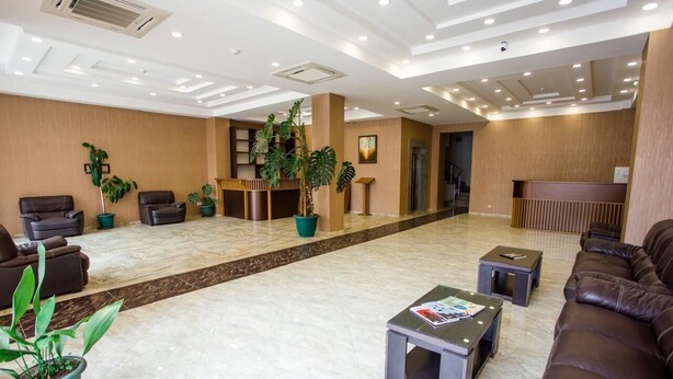 A spacious lobby with a reception desk, seating area, and potted plants. - Rio Batumi (Batumi)
