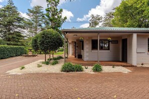 A building with a covered porch, a sign indicating 'Administration,' and a well-maintained garden with a fountain and trimmed bushes. - Administration House Winery Stay (Tamborine Mountain)