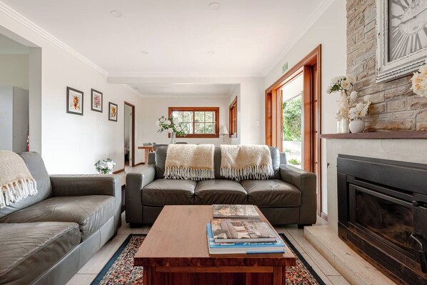 A living room with a fireplace, a sofa, a coffee table, and a dining area.
