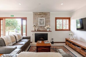 A living room with a fireplace, a sofa, a coffee table, and a TV.