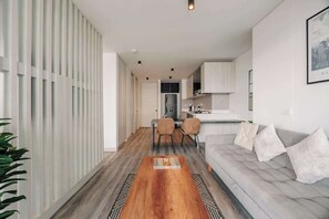 Ein modernes Wohnzimmer mit einer Couch, einem Essbereich mit Stühlen und einer Küche im Hintergrund.