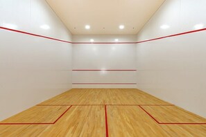 Een squashbaan met houten vloer en rode lijnen.