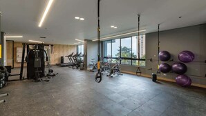 Et fitnesscenter med træningsudstyr, store vinduer og højt til loftet.