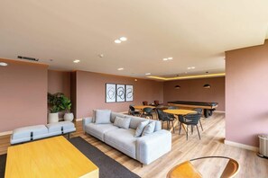 Ein modernes Wohnzimmer mit einer Couch, einem Couchtisch, einem Essbereich mit Stühlen und einem Tisch sowie einem Billardtisch.