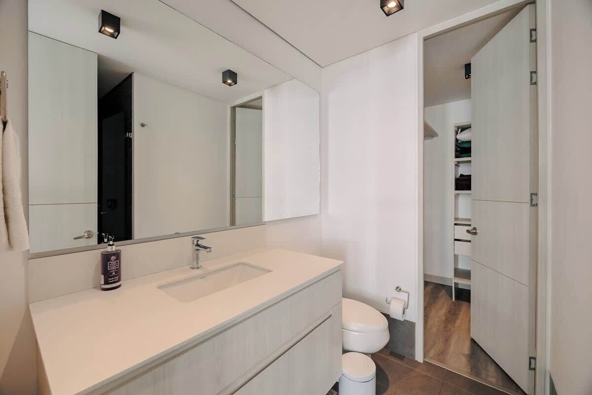 A modern bathroom with a white vanity, a large mirror, and a toilet.