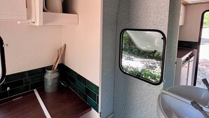 Uma cozinha compacta com pia embutida, uma janela com vista e um pequeno armário com utensílios.