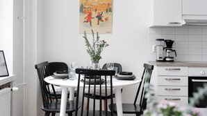 Uma área de refeições com uma mesa branca, cadeiras pretas e um cartaz na parede.