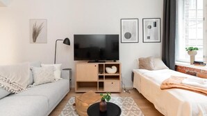 Uma sala de estar moderna com sofá, cama, televisão e mesa de centro.