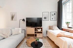 Moderni olohuone, jossa on sohva, sänky, televisio ja sohvapöytä.