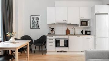A modern kitchen with white cabinets, a microwave, an oven, and a dining area with a table and chairs.