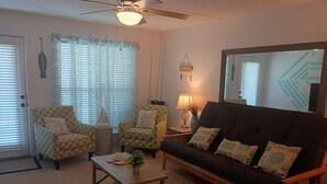 Ein Wohnzimmer mit einer Couch, zwei Sesseln, einem Couchtisch und einem Deckenventilator.