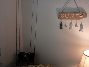 A room with a fishing rod, a surf-themed sign, and a lamp. - Seascape Escape 304 (South Padre Island)
