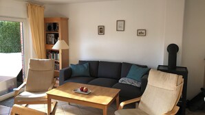 Un salon comprenant un canapé, deux fauteuils, une table basse en bois, une bibliothèque et une cheminée.