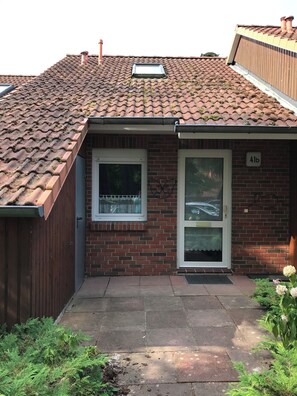 Ein Backsteinhaus mit Ziegeldach, kleinem Fenster und einer Tür.