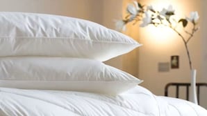 Un lit avec une literie blanche et une lampe de chevet.