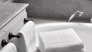 Une salle de bain avec une baignoire, deux serviettes suspendues à un porte-serviettes et un comptoir en marbre.