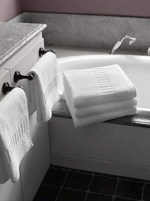A bathroom with a bathtub, two towels hanging on a towel rack, and a marble countertop. - Wonderful 2-beds with AC by Leicester Square (London)