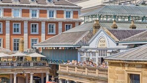 Un marché animé en plein air, avec une grande variété de boutiques et de restaurants, dont un établissement bien visible appelé « Punch & Judy ».