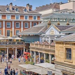 A bustling outdoor market area with a variety of shops and eateries, including a visible restaurant named 'Punch & Judy.' - Wonderful 2-beds with AC by Leicester Square (London)