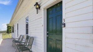 A white building with a green door, numbered 3, and a porch with metal chairs. - Charming Apartment w/ Shared Deck & Lake Views (Lawrenceville)