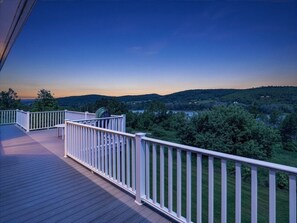 A wooden deck with white railings overlooking a green landscape.