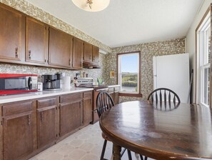 A kitchen with wooden cabinets, a dining table, and a view of the outdoors.
