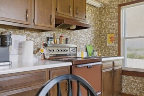 Une cuisine avec des meubles de rangement en bois, une cuisinière et une fenêtre.