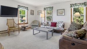 Un salon comprenant un téléviseur, un canapé, un fauteuil et une table basse.