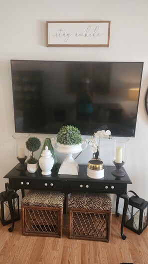 A black entertainment center with decorative items, a television, and a framed sign above. - Florida Fun Villa in the heart of Oldsmar between Tampa and Clearwater (Oldsmar)