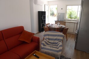 A compact living space with a red sofa, a striped armchair, and a dining table set for two. - Waterfront house with 2 bedrooms, living room, air conditioning, pool, and secure parking (Le Barcarès)