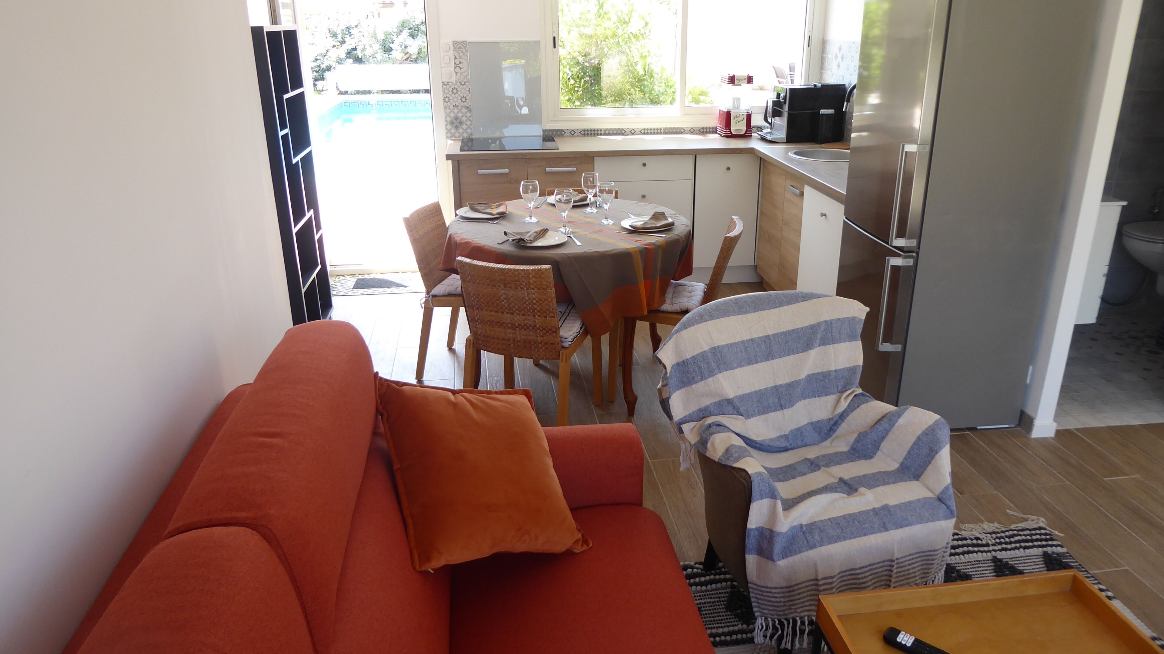 A compact living space with a sofa, a dining table set for four, and a kitchen area.