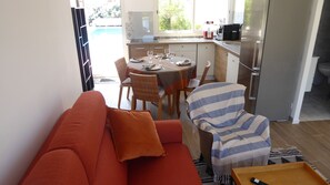 A compact living space with a sofa, a dining table set for four, and a kitchen area. - Waterfront home with 2 bedrooms, living room, air conditioning, pool, and secure parking (Le Barcarès)