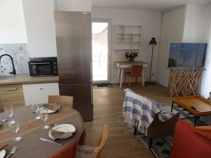A compact kitchen with a stainless steel refrigerator, a microwave, and a dining area with a table set for four. - Waterfront home with 2 bedrooms, living room, air conditioning, pool, and secure parking (Le Barcarès)