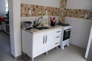 Una cocina compacta con lavamanos, estufa y microondas.