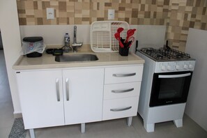 A compact kitchen with a gas stove, a sink, and a microwave. - Azure Riviera Ferrugem (Garopaba)